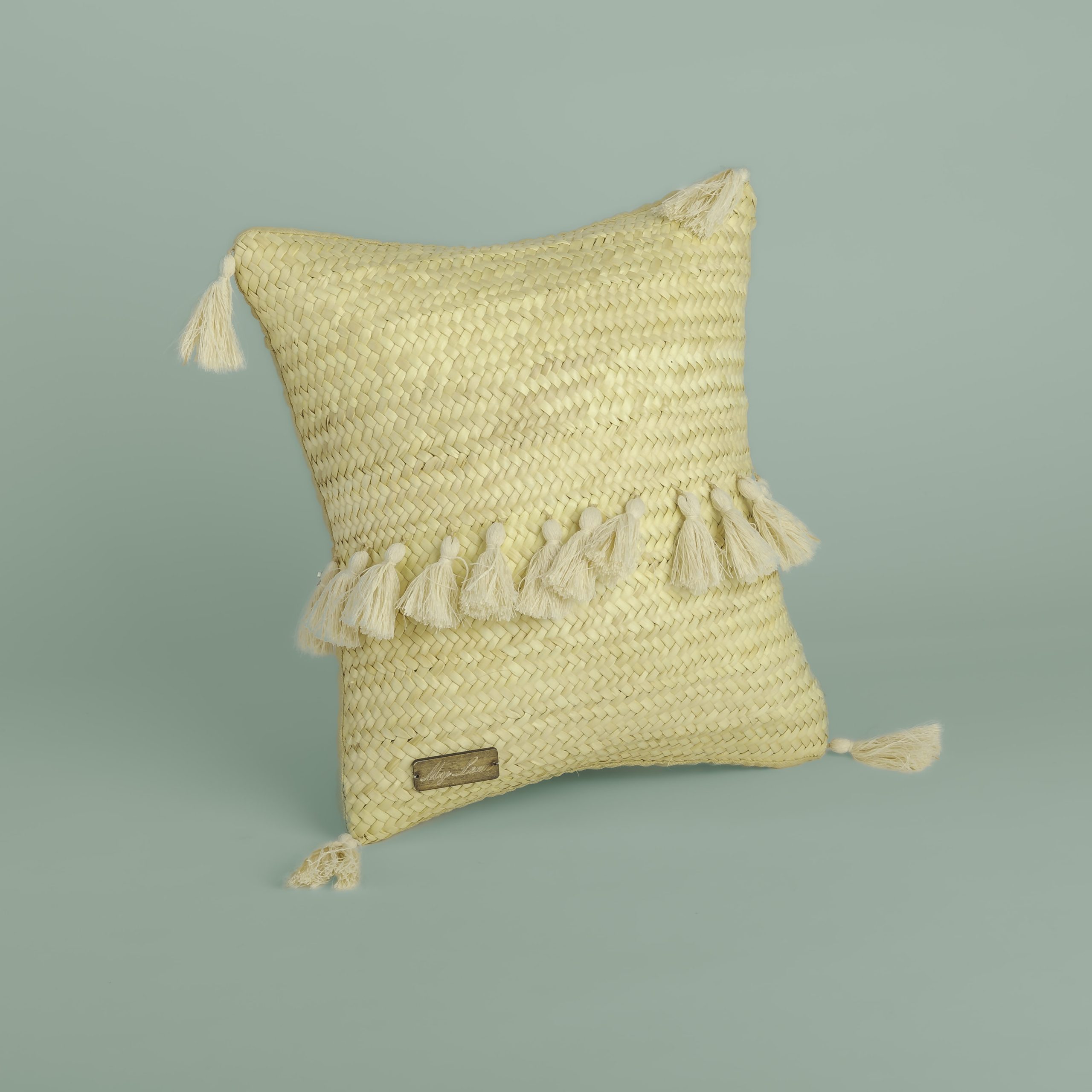 Coussin en paille tressée avec pompons